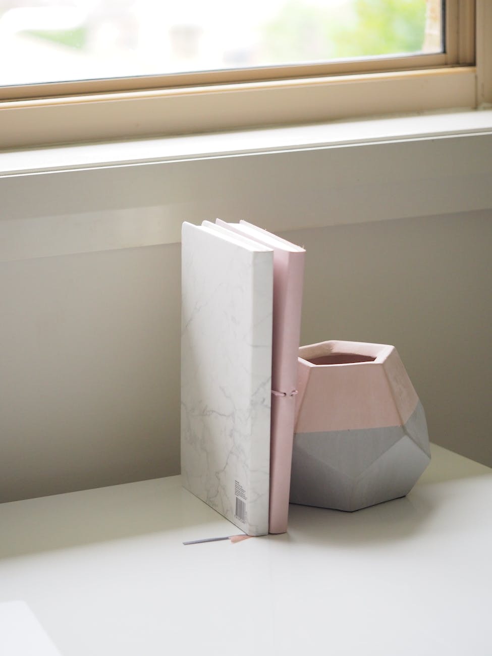 white and pink books piled beside pink and gray ceramic vase